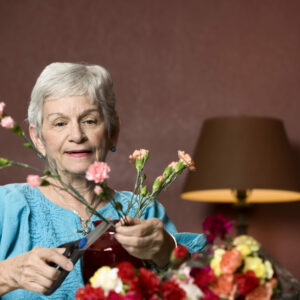 Senior woman at home with colorful flowers